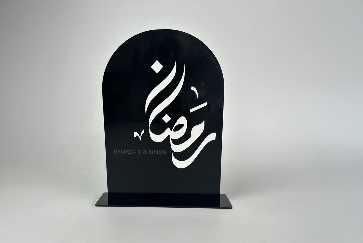 قوس من الأكريليك الأسود كُتب عليه «رمضان» بخط أبيض، من قبة «رمضان كريم – عيد مبارك» ذات الوجهين