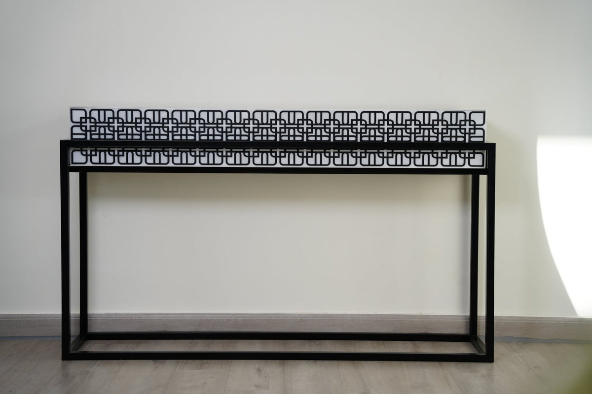 A black metal console table with a band of cut geometric pattern along its top; made to order by MASHQ