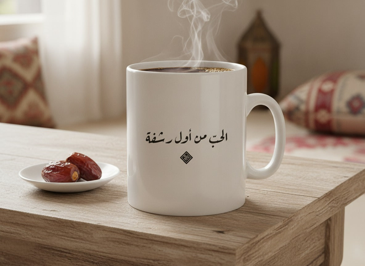 «الحبّ من أول رشفة» in Ruq'ah printed on a ceramic mug, photographed on a table