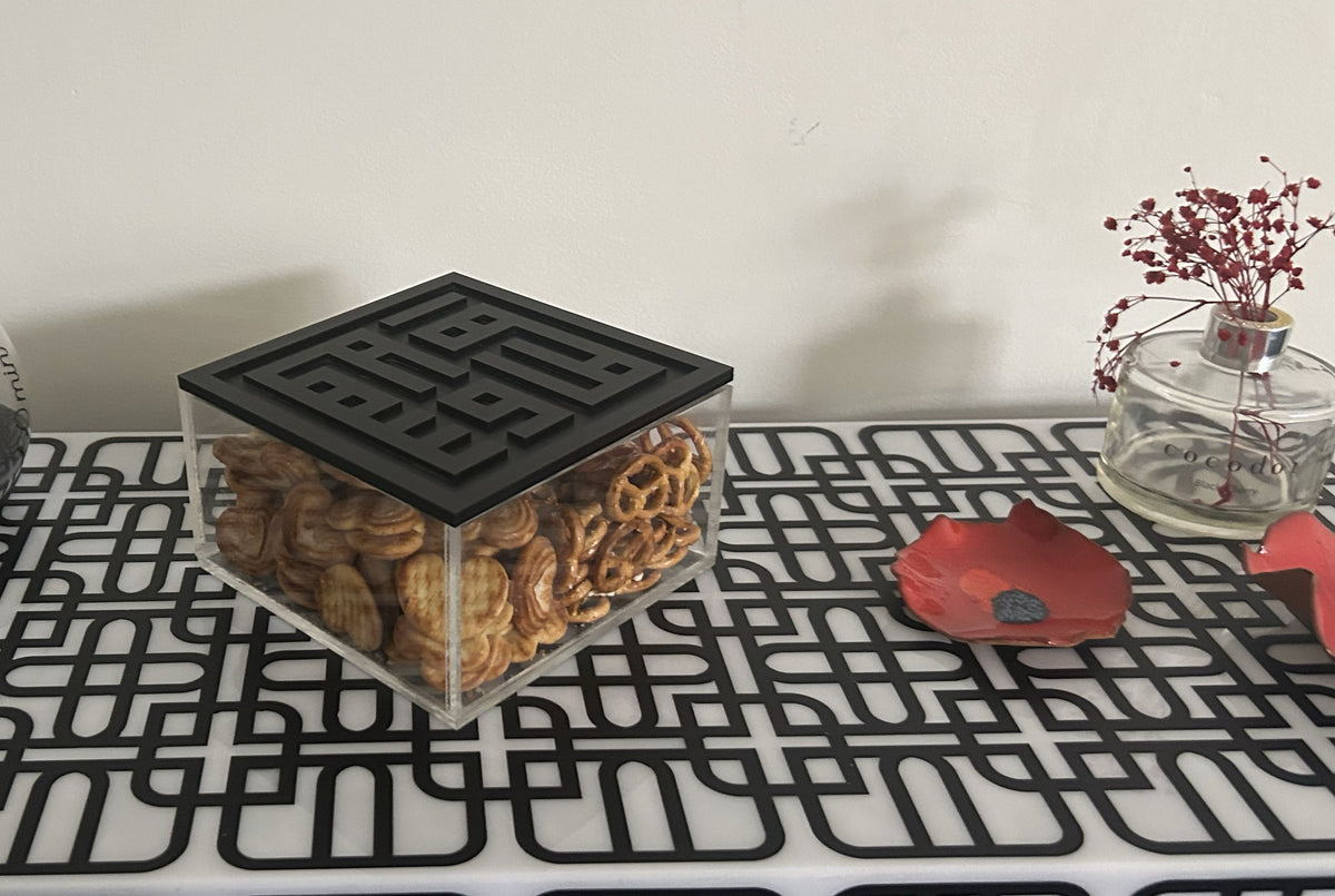 Acrylic box of nuts with a black Kufic lid, on a patterned console table