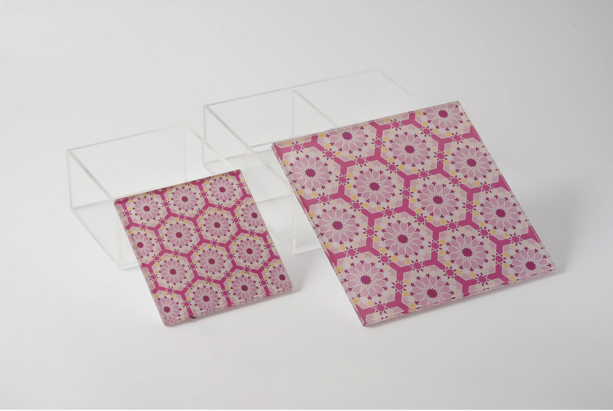 Pair of clear acrylic boxes with pink arabesque lids, closed