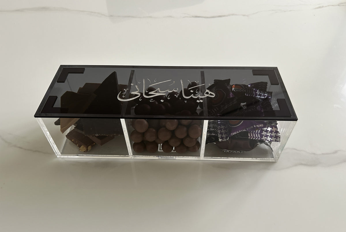 Divided acrylic box filled with dates and nuts under a black calligraphy lid