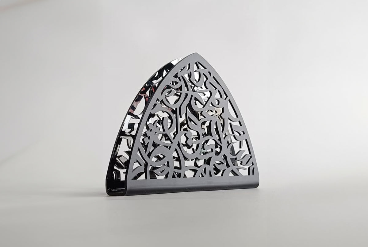Black arabesque napkin holder photographed against a white ground