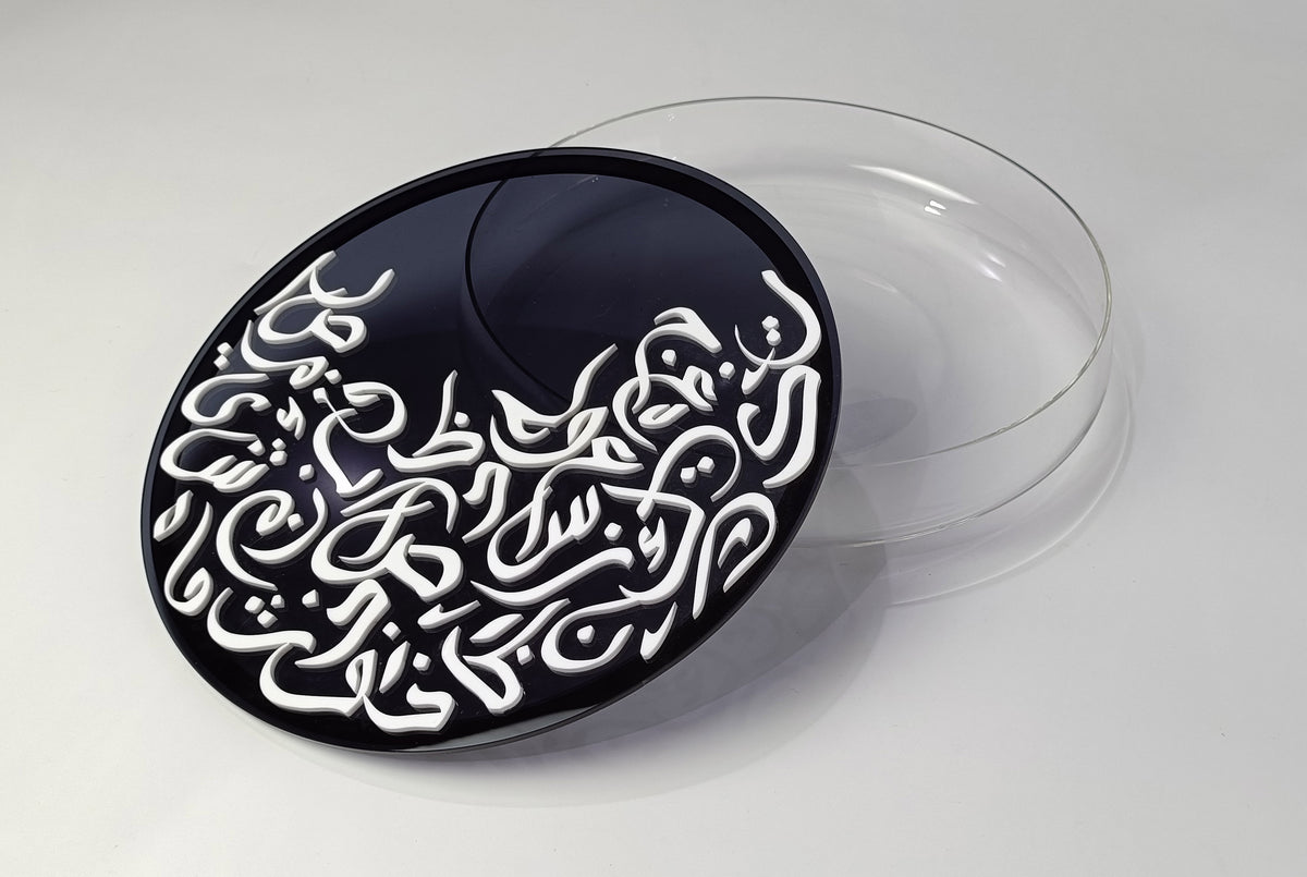 Round black calligraphy lid resting on a clear glass dish