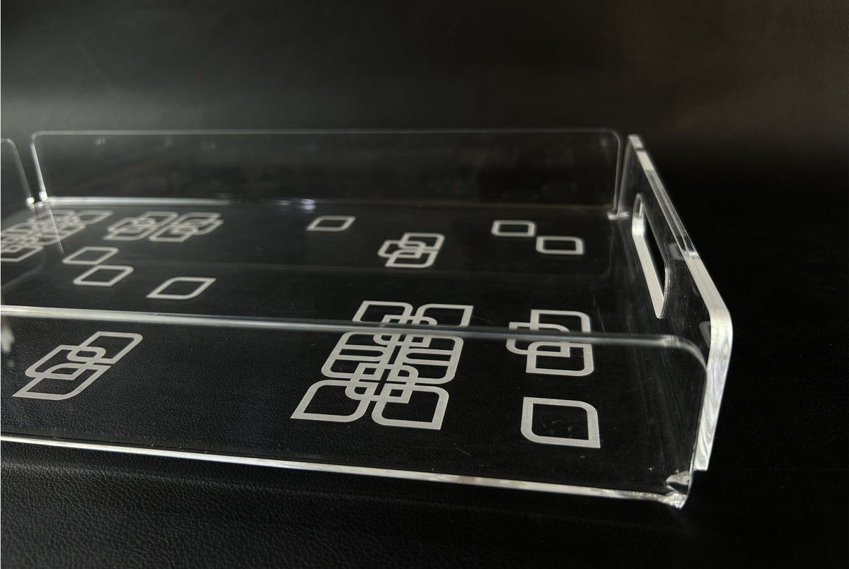 Clear acrylic tray with white square motifs, on a dark surface