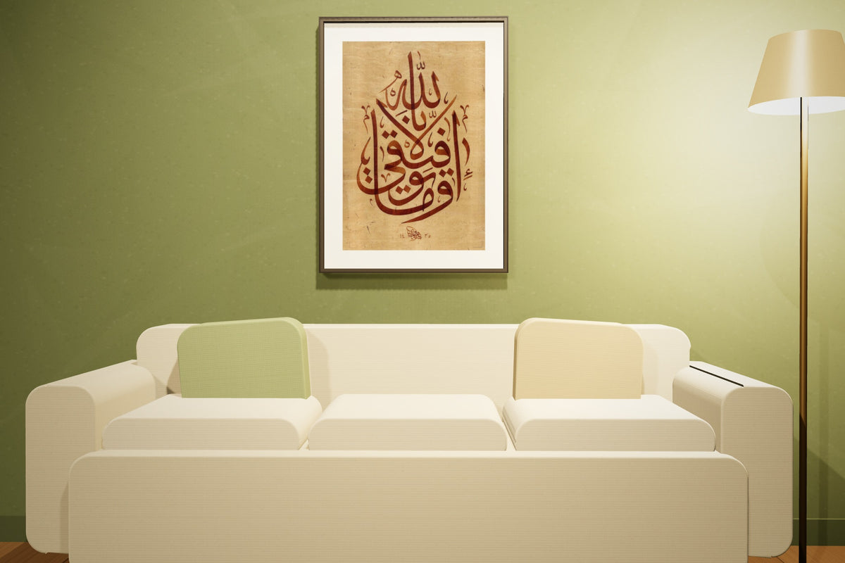 «وما توفيقي إلا بالله» بخط أحمد الهواري، 50 × 70 سم، معروضة بمقاسها الحقيقي في إطار أسود رفيع في صالة زيتونية اللون — التأطير متاح عند الطلب