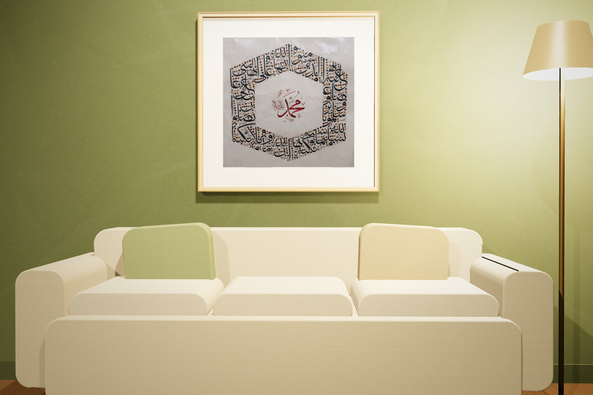 Two works, «أسماء الله الحسنى» and «محمد صلى الله عليه وسلم», framed — natural oak frame, in an olive lounge