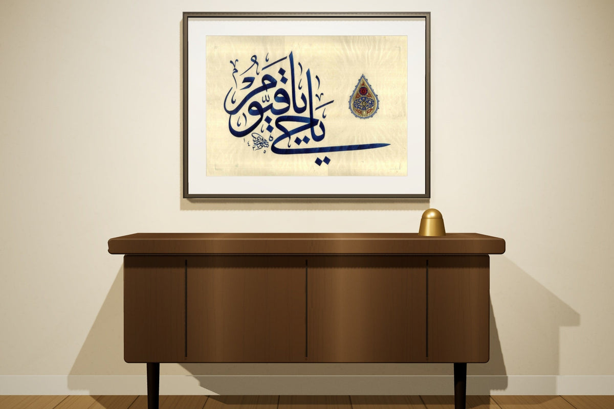 Ahmed Alhawary's original «يا حي يا قيوم» in blue Jali Thuluth with a gilded shamsa, framed above a walnut sideboard
