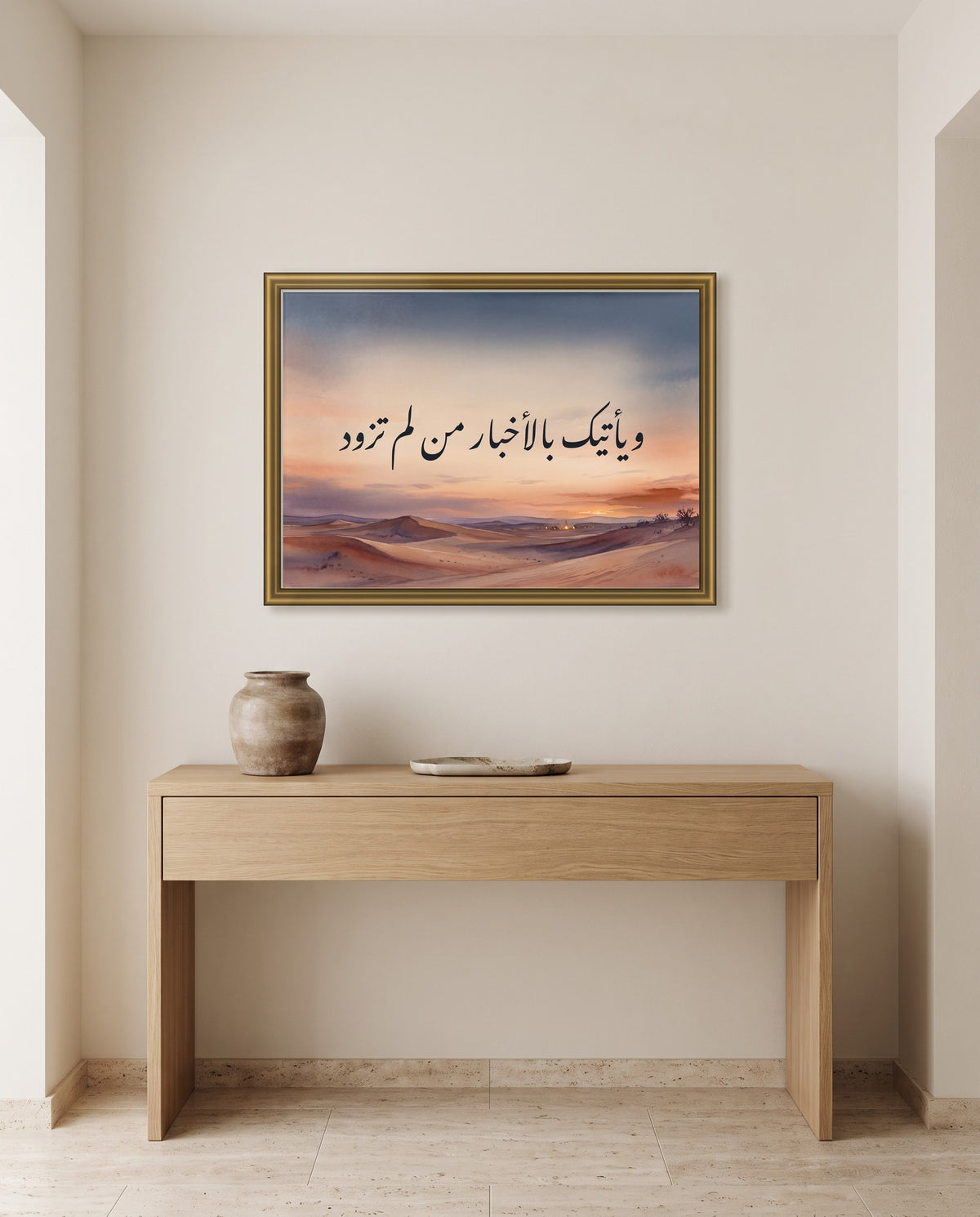 «ويأتيك بالأخبار من لم تزود» بخط النستعليق في إطار ذهبي مصقول فوق طاولة كونسول من البلوط في مدخل البيت