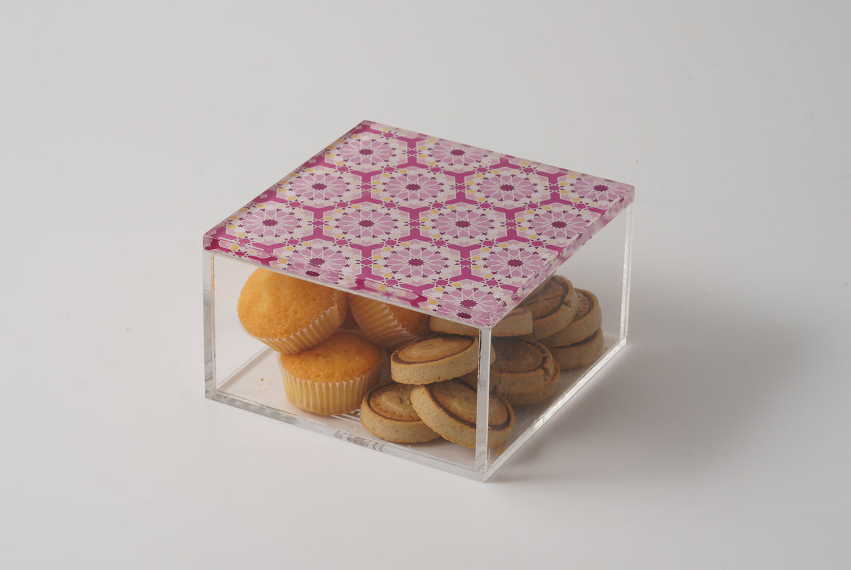 Clear acrylic box with a pink arabesque lid, open, filled with biscuits
