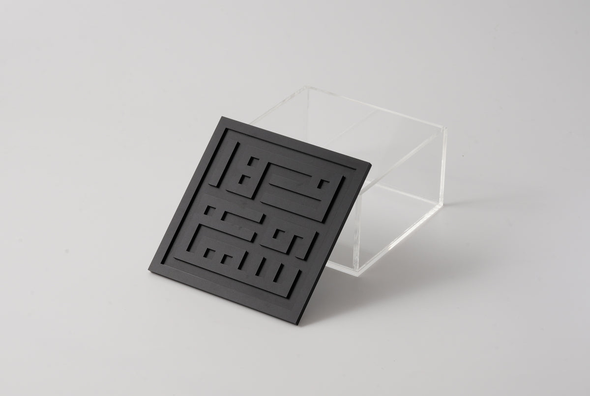 Clear acrylic box with a black square-Kufic lid set across the opening