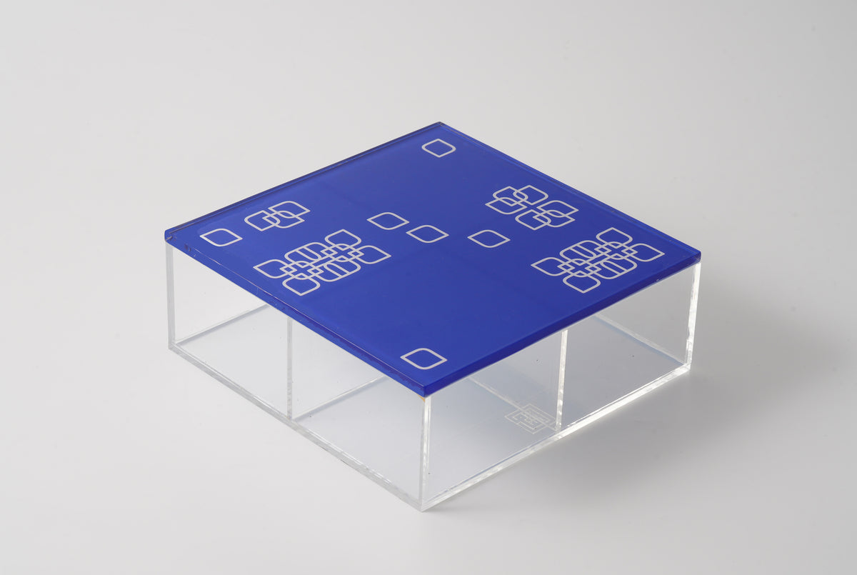 Blue lid with white square motifs on a clear square acrylic box