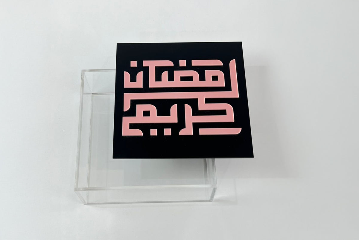 غطاء أسود «رمضان كريم» بحروف وردية على علبة أكريليك شفافة