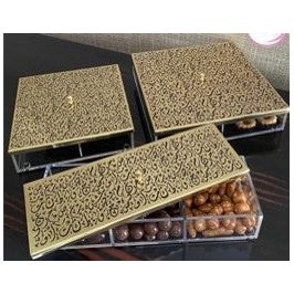 Three gold Diwani-patterned lids on a divided acrylic box filled with dates