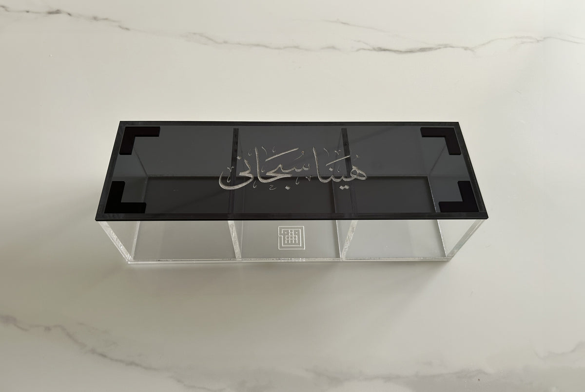 Divided clear acrylic box with a black lid carrying white Thuluth calligraphy