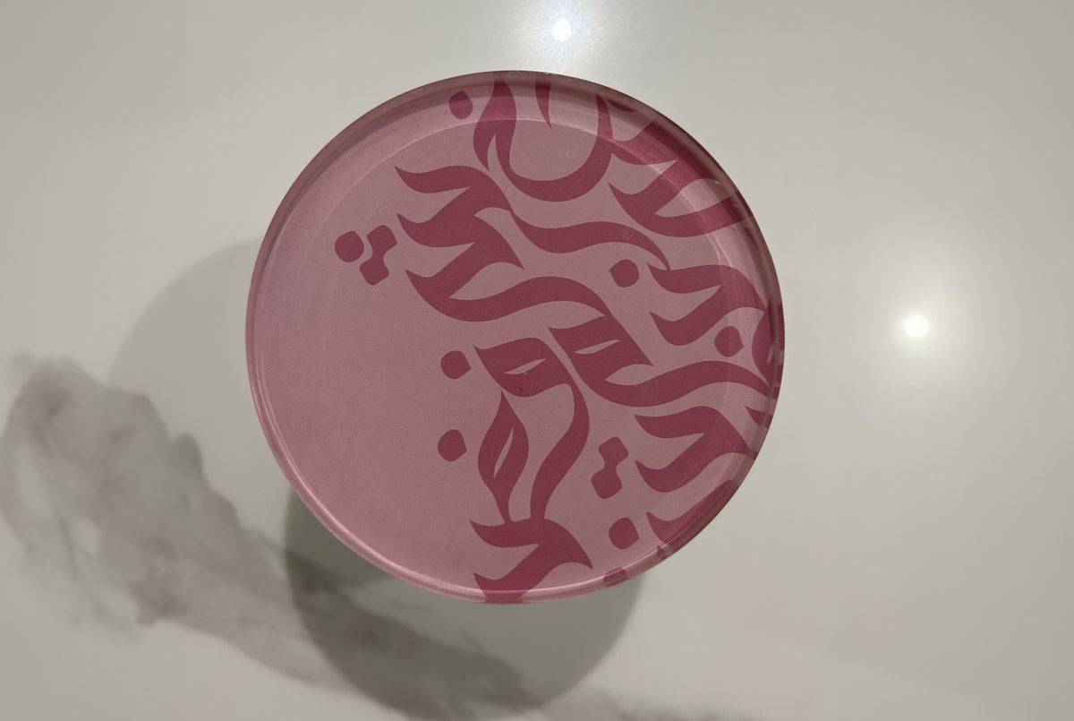 Close-up of a pink jar lid engraved with Arabic calligraphy