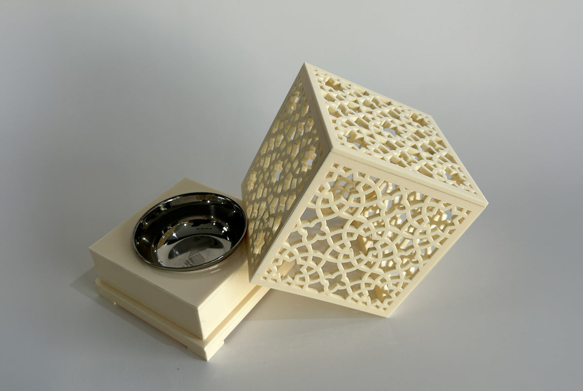 Gold pierced arabesque box with the lid tilted open beside a small black incense bowl