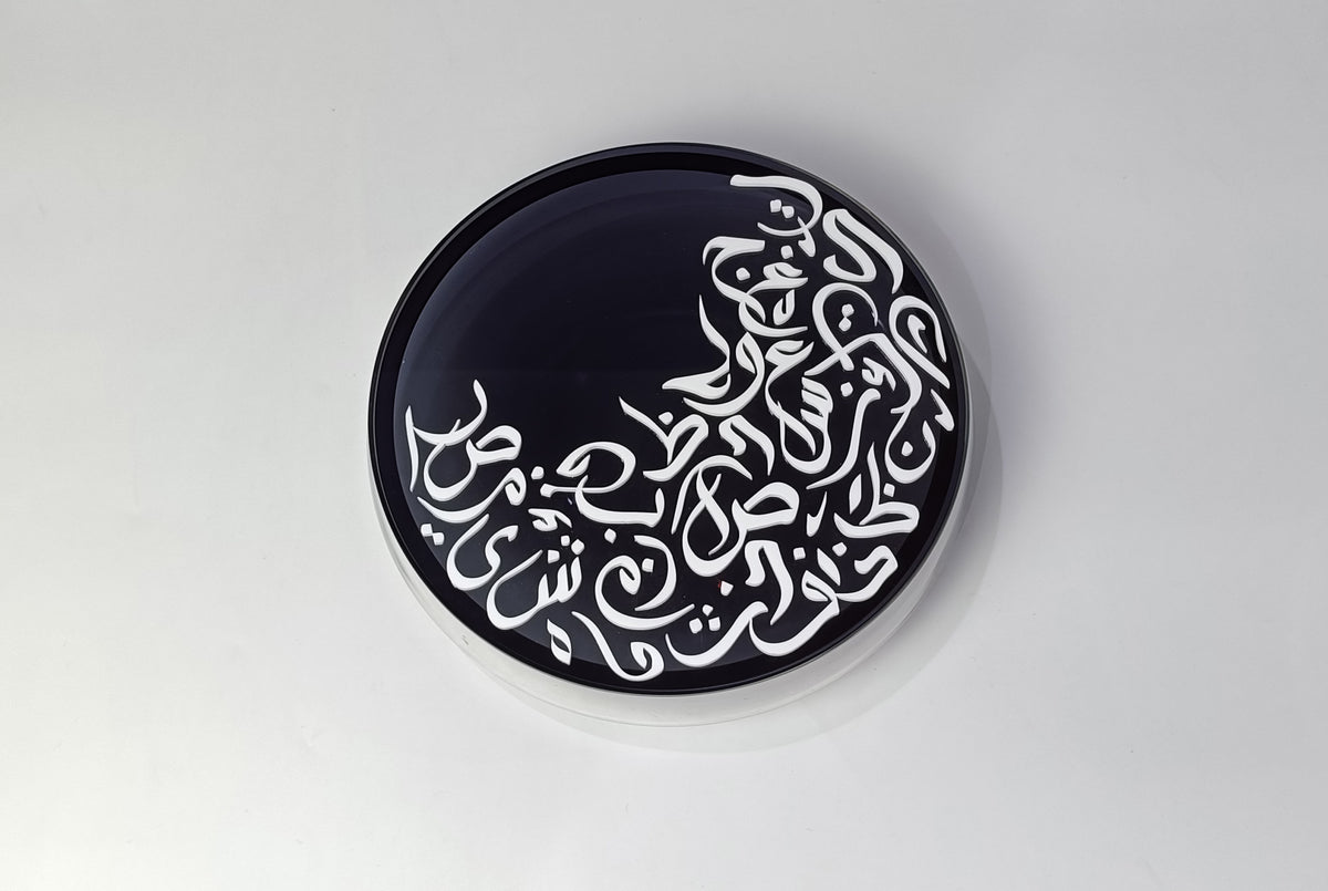 Round black lid with white Arabic calligraphy, viewed from above