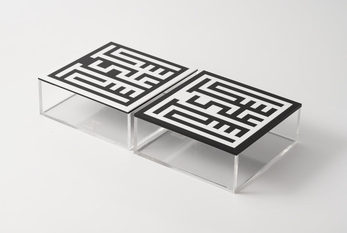 Two clear acrylic boxes with black square-Kufic lids, side by side