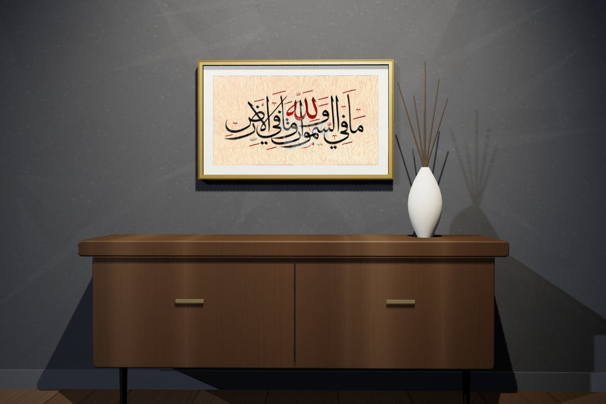 «لله ما في السموات وما في الأرض» بخط أحمد الهواري، 70 × 50 سم، معروضة بمقاسها الحقيقي في إطار بورق الذهب في شقة علوية — التأطير متاح عند الطلب