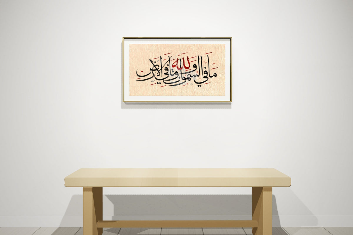 «لله ما في السموات وما في الأرض» بخط أحمد الهواري، 70 × 50 سم، معروضة بمقاسها الحقيقي في إطار نحاسي رفيع على جدار معرض — التأطير متاح عند الطلب