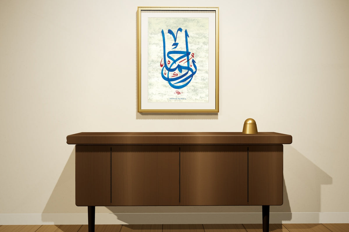 «رحماك» بخط أحمد الهواري، 50 × 70 سم، معروضة بمقاسها الحقيقي في إطار بورق الذهب على جدار مجلس — التأطير متاح عند الطلب