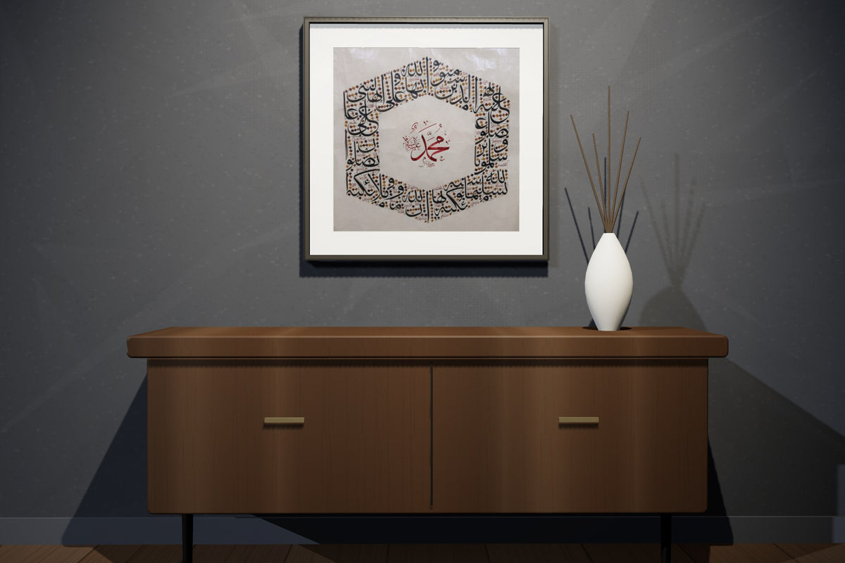 Two works, «أسماء الله الحسنى» and «محمد صلى الله عليه وسلم», framed — slim black frame, in a charcoal loft