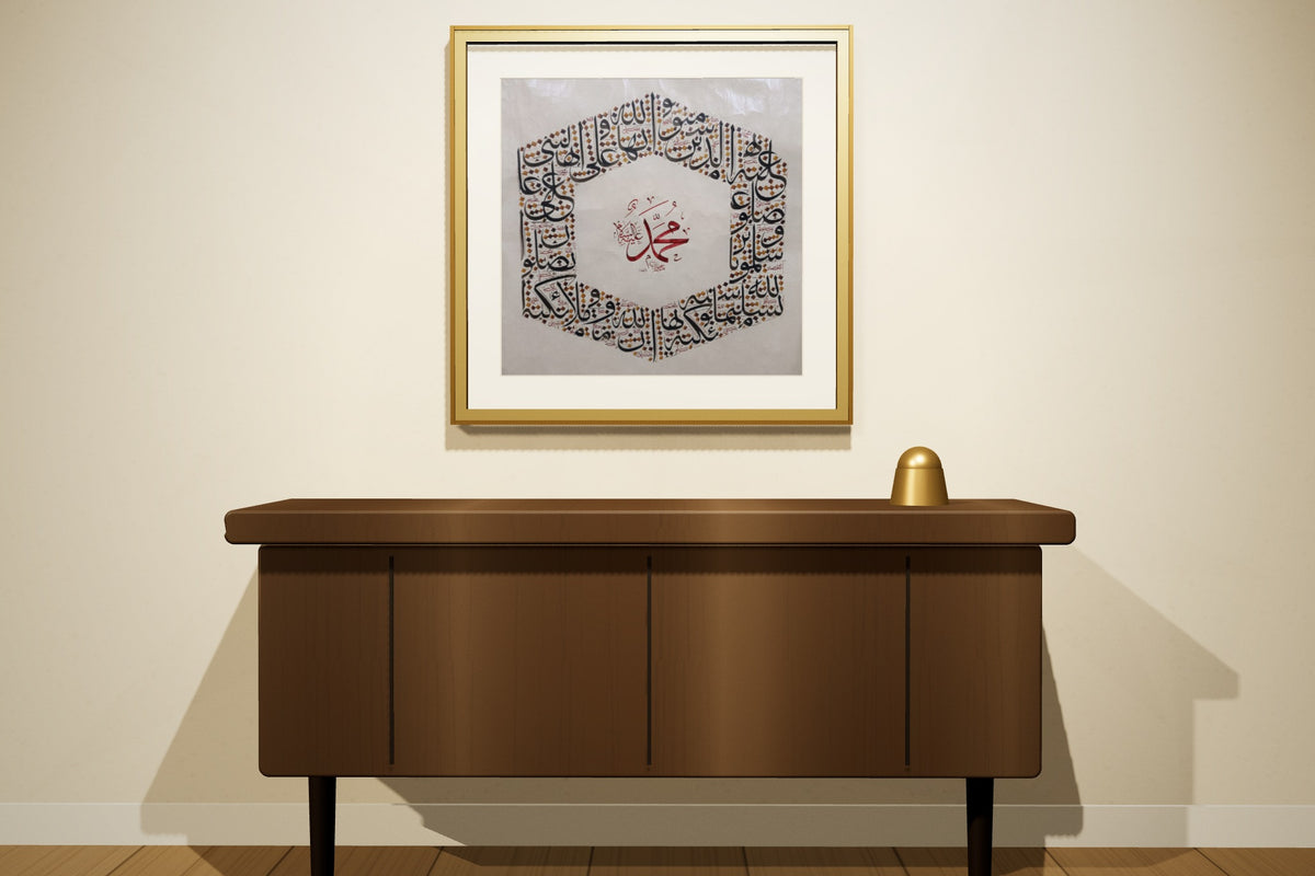 Two works, «أسماء الله الحسنى» and «محمد صلى الله عليه وسلم», framed — gold leaf frame, in a majlis