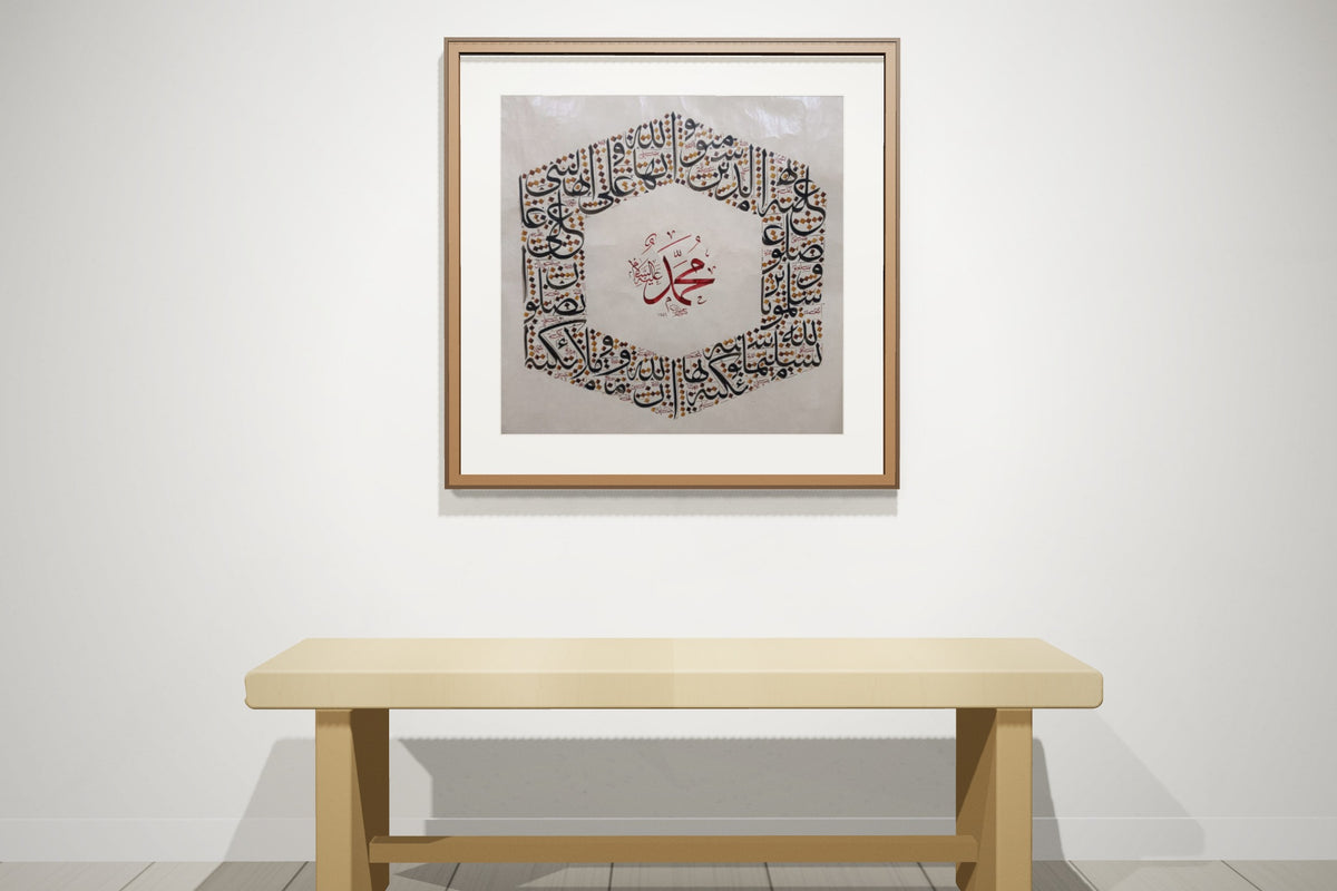 Two works, «أسماء الله الحسنى» and «محمد صلى الله عليه وسلم», framed — dark walnut frame, on a gallery wall