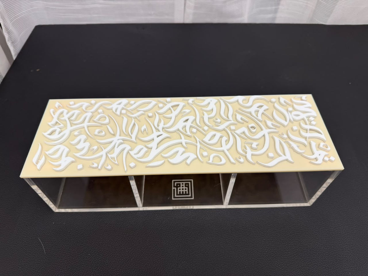 Clear acrylic dates box with three compartments under a cream lid of raised white Sunbuli calligraphy letters, made to order by MASHQ